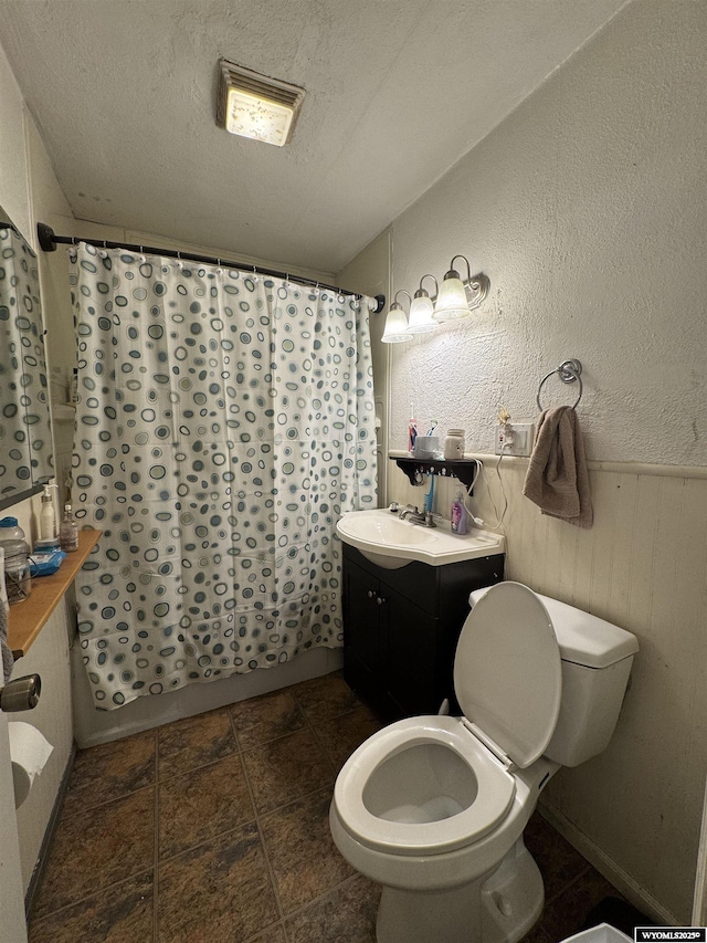 117 W Madison, Riverton, WY 82501 - bathroom featuring toilet, shower / tub combo with curtain, a textured ceiling, vanity, and stone finish flooring
