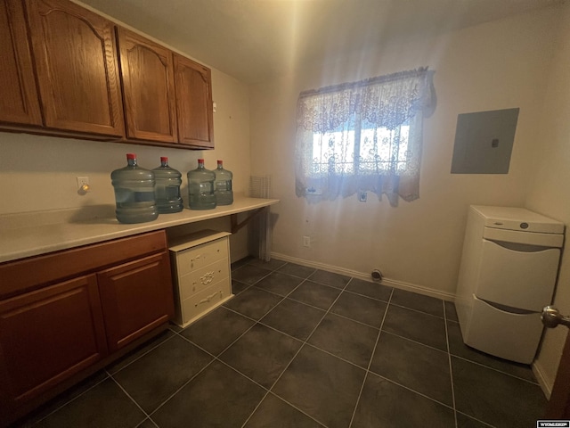 washroom featuring electric panel, washer / dryer, baseboards, and dark tile patterned flooring