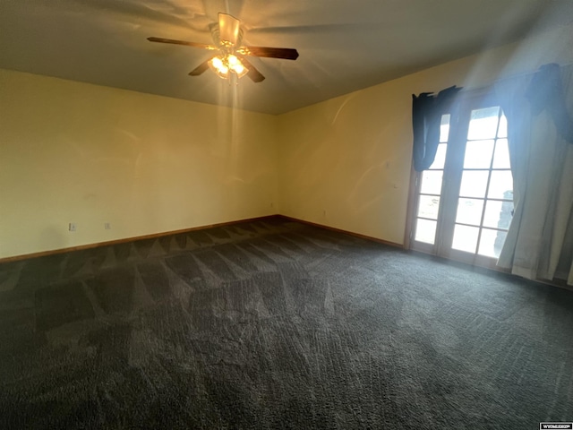 empty room featuring dark carpet, baseboards, and a ceiling fan
