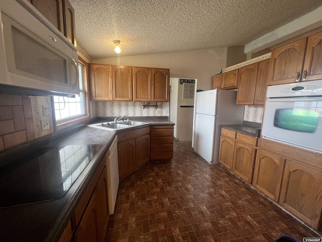 kitchen with white appliances, a textured ceiling, a sink, and lofted ceiling