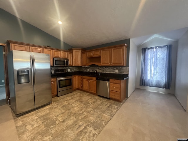 kitchen featuring stainless steel appliances, dark countertops, decorative backsplash, and lofted ceiling