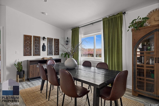 dining space featuring light wood-style flooring and lofted ceiling