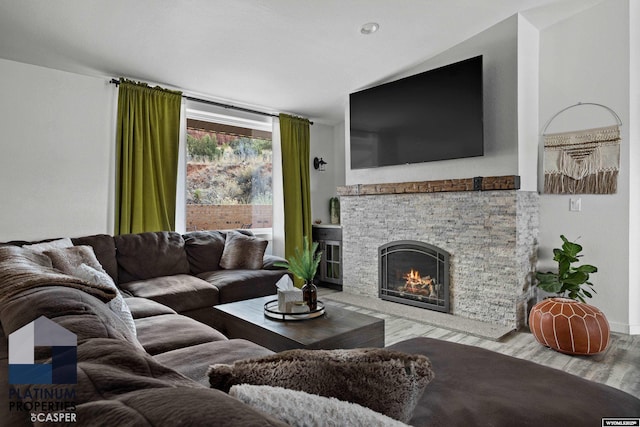 living area featuring baseboards, vaulted ceiling, wood finished floors, and a fireplace