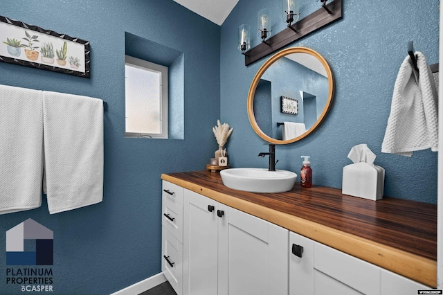 bathroom with vanity, baseboards, and a textured wall