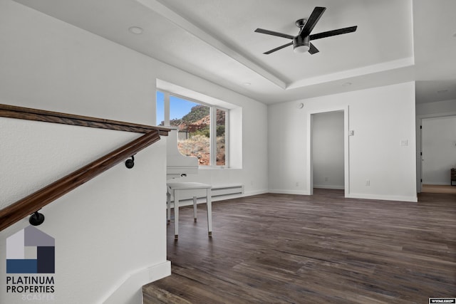 unfurnished living room with a tray ceiling, ceiling fan, baseboards, and dark wood finished floors