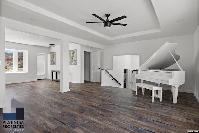 interior space featuring a raised ceiling, wood finished floors, ceiling fan, and baseboards
