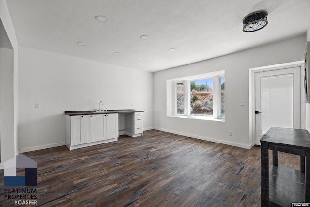 interior space with a sink, baseboards, recessed lighting, and dark wood-type flooring