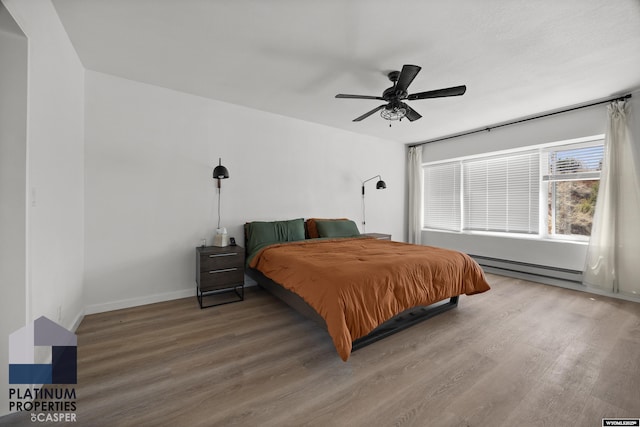 bedroom with baseboards, ceiling fan, a baseboard heating unit, and wood finished floors
