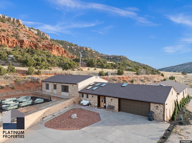 view of front of property with solar panels, brick siding, an attached garage, a mountain view, and driveway