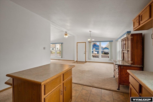 kitchen with brown cabinetry, a kitchen island, vaulted ceiling, light carpet, and open floor plan