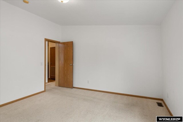 unfurnished room featuring visible vents, baseboards, vaulted ceiling, and light carpet
