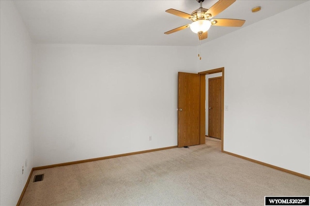 spare room featuring a ceiling fan, visible vents, light colored carpet, and baseboards