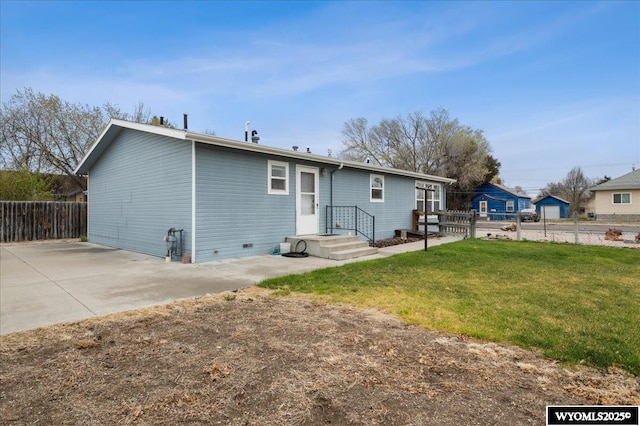 rear view of property featuring fence, a lawn, and a patio