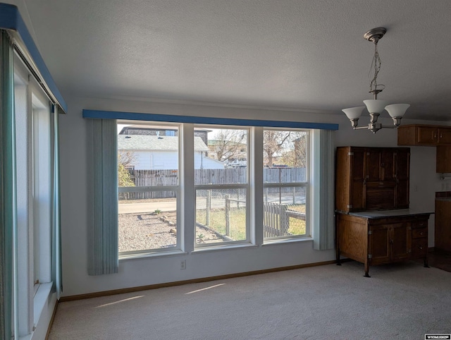unfurnished living room featuring a wealth of natural light, a textured ceiling, and light colored carpet