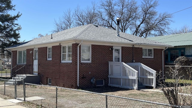 view of front of property with a shingled roof, a fenced backyard, and brick siding