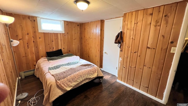 bedroom featuring a baseboard heating unit, wood finished floors, and wooden walls
