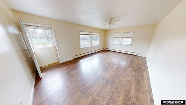 empty room with a baseboard heating unit, baseboards, a ceiling fan, and wood finished floors