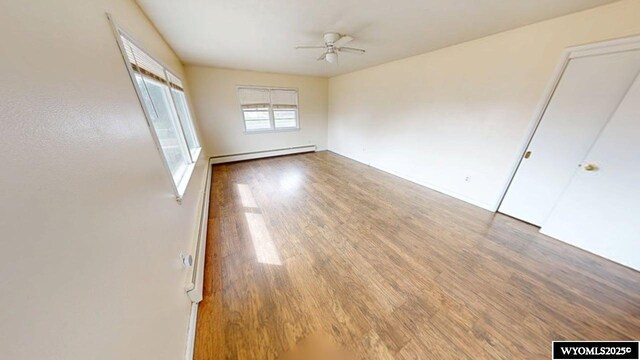 unfurnished bedroom featuring baseboard heating, baseboards, and wood finished floors