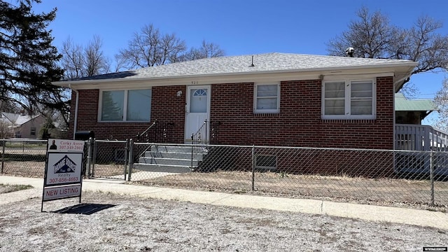 bungalow-style house with fence private yard, a gate, brick siding, and roof with shingles