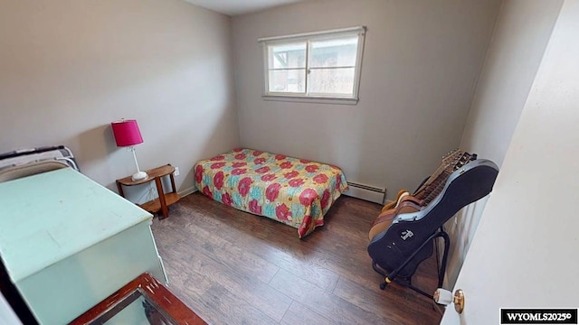 bedroom with a baseboard heating unit and wood finished floors