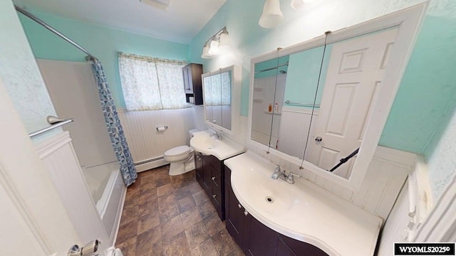 full bathroom with a baseboard radiator, wainscoting, vanity, toilet, and stone finish floor