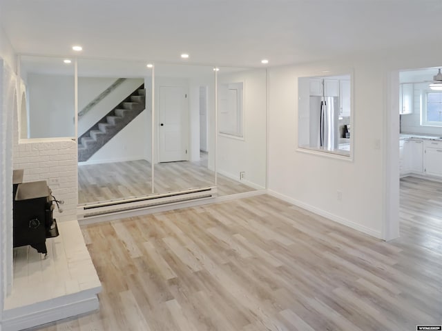 unfurnished living room with light wood-style flooring, baseboards, recessed lighting, and stairway