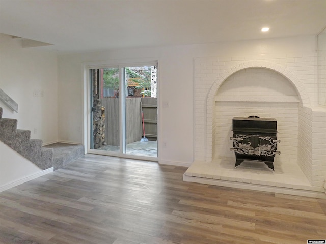 unfurnished living room with stairway, wood finished floors, a fireplace, baseboards, and recessed lighting