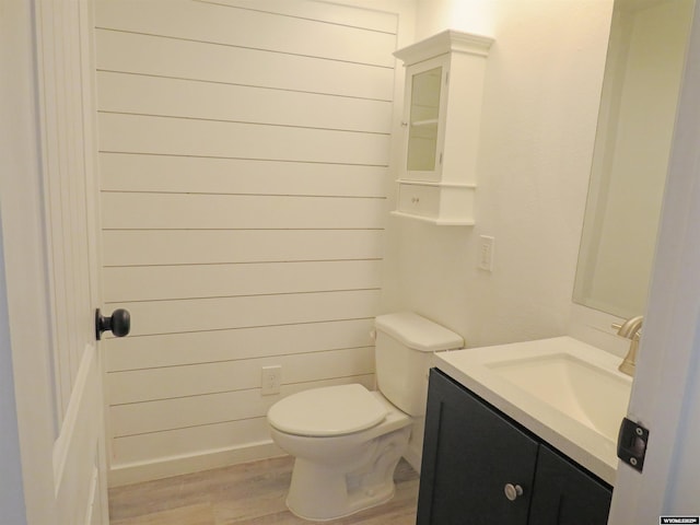 bathroom with toilet, vanity, and wood finished floors