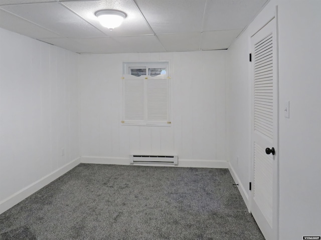 empty room with a baseboard heating unit, a paneled ceiling, baseboards, and carpet floors