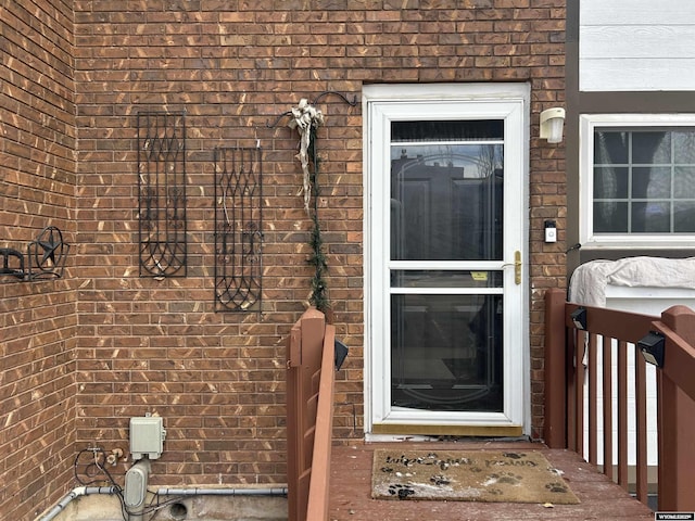 view of exterior entry featuring brick siding