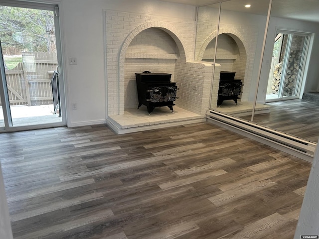 unfurnished living room featuring baseboards, a wood stove, wood finished floors, and recessed lighting