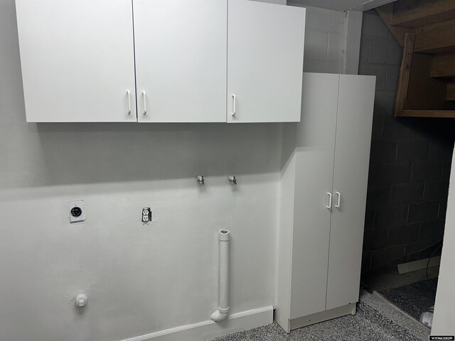 clothes washing area with concrete block wall and hookup for an electric dryer