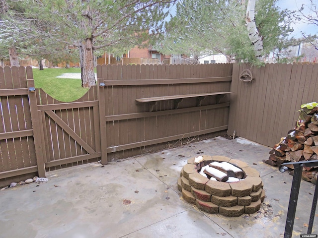 view of gate featuring fence, a patio area, and an outdoor fire pit
