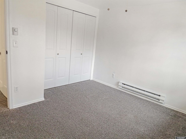 unfurnished bedroom featuring a baseboard heating unit, baseboards, carpet, and a closet