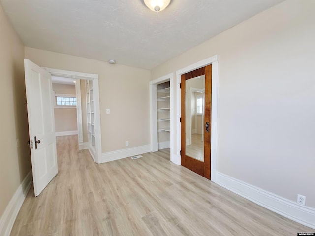 empty room featuring baseboards, visible vents, and light wood-type flooring
