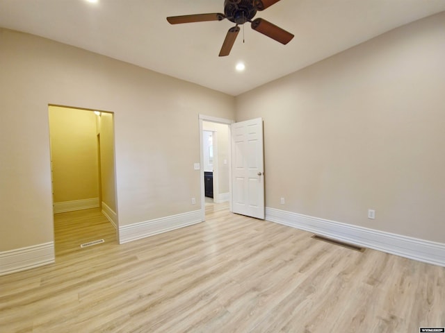 spare room with light wood-type flooring, visible vents, a ceiling fan, and baseboards
