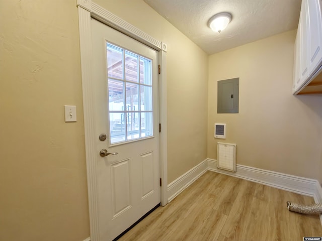laundry room featuring electric panel, light wood-type flooring, baseboards, visible vents, and cabinet space