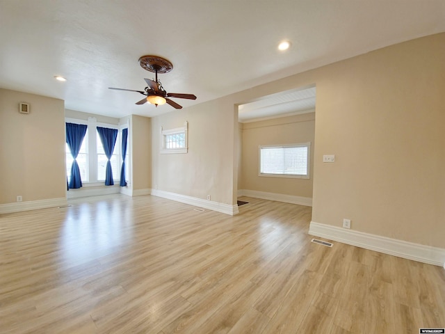 spare room with a ceiling fan, visible vents, light wood-style floors, and a healthy amount of sunlight