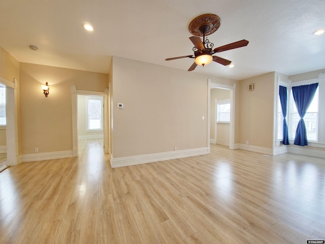 empty room featuring ceiling fan, baseboards, light wood-style flooring, and plenty of natural light