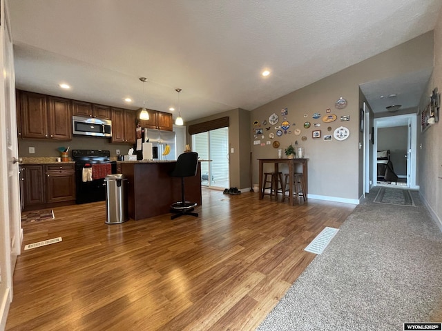 kitchen featuring stainless steel appliances, light countertops, visible vents, light wood-type flooring, and a kitchen island