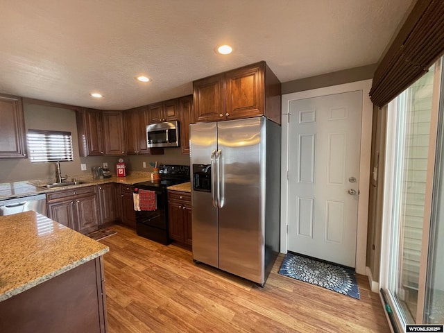 kitchen featuring light wood finished floors, a sink, recessed lighting, and appliances with stainless steel finishes