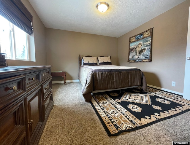 bedroom featuring a textured ceiling, carpet flooring, and baseboards