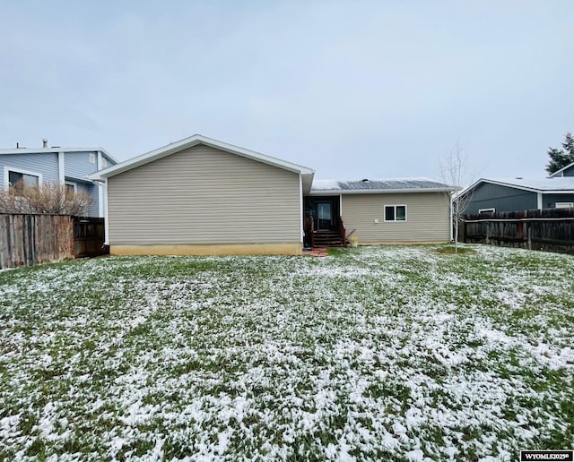 snow covered rear of property featuring fence and entry steps