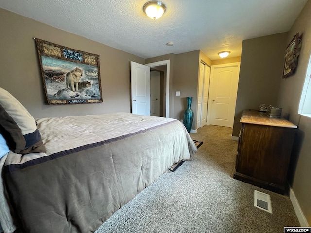 bedroom with visible vents, carpet floors, a closet, baseboards, and a textured ceiling