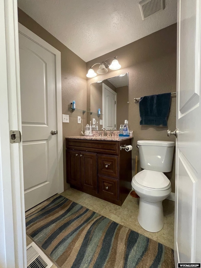 half bathroom with a textured ceiling, visible vents, toilet, and vanity