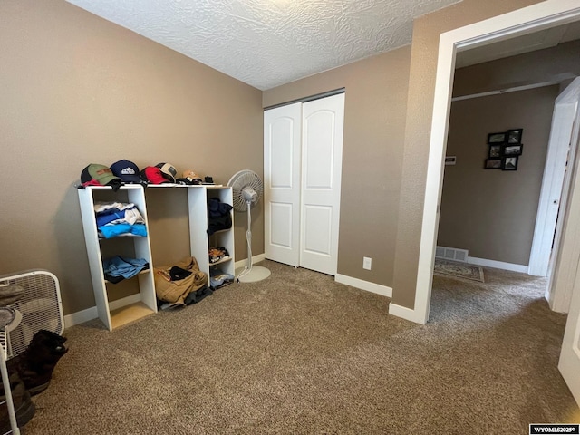 carpeted bedroom with baseboards, a textured ceiling, visible vents, and a closet