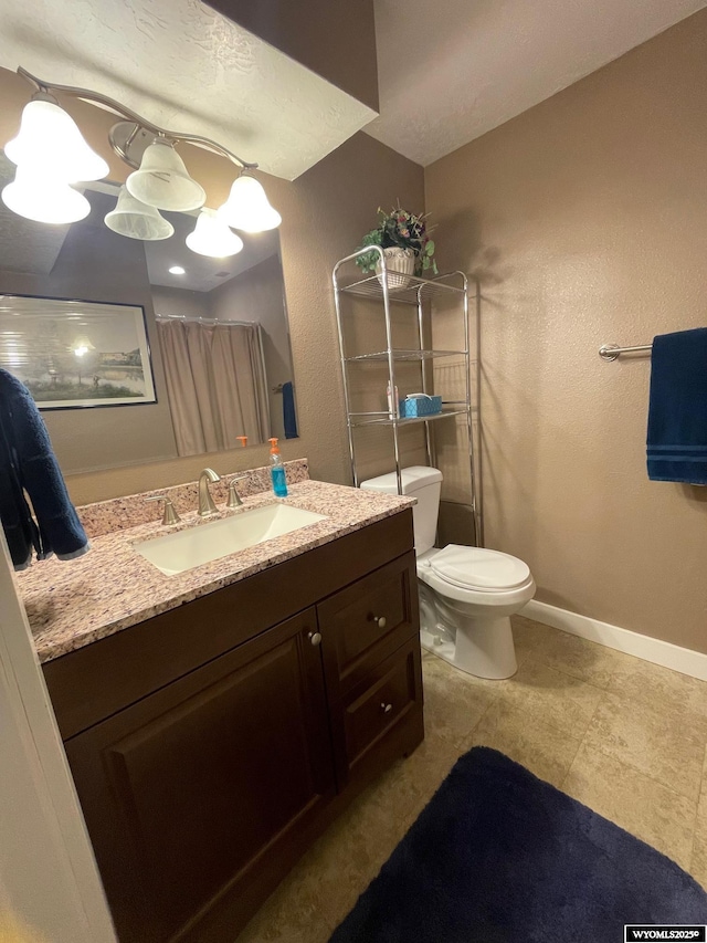 bathroom featuring toilet, vanity, and baseboards