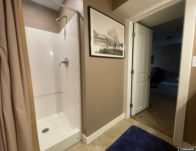 bathroom with baseboards and a shower stall