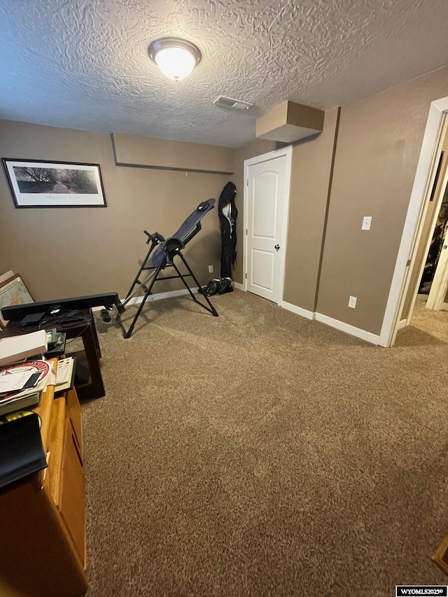 exercise area featuring baseboards, visible vents, carpet, and a textured ceiling