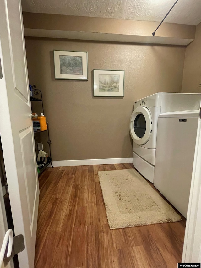 washroom featuring a textured ceiling, baseboards, wood finished floors, independent washer and dryer, and laundry area